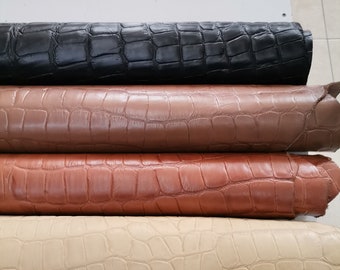 May include: Four rolls of crocodile embossed leather in different colors: black, brown, tan, and beige.