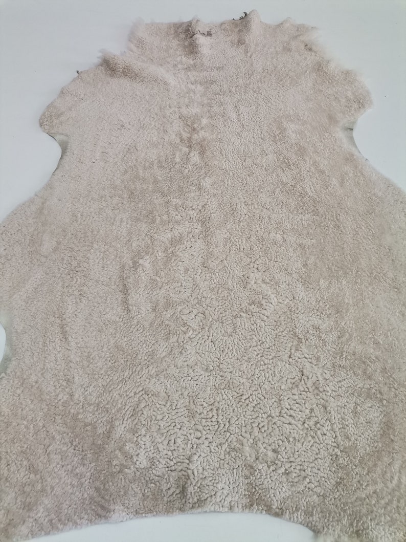 May include: A cream-colored sheepskin rug with a soft, fluffy texture.