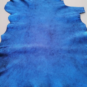 May include: A piece of blue leather with a metallic sheen. The leather is smooth and has a slight texture.