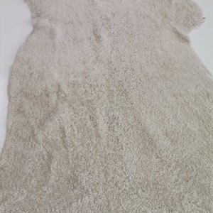 May include: A light beige sheepskin rug with a soft, fluffy texture.