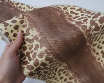 Könnte beinhalten: Nahaufnahme eines braunen und beigen Stoffes mit Leopardenmuster. Der Stoff ist texturiert und hat einen leichten Glanz.