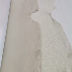 May include: A piece of off-white leather with a white fleece backing. The leather is smooth and the fleece is soft and fluffy.