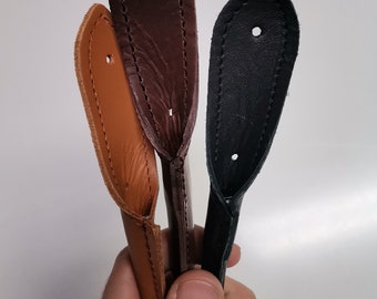 Peut inclure: Trois lanières en cuir de couleur marron, beige et noir. Chaque lanière a un seul trou près du haut.