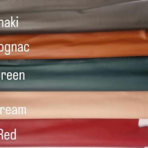 May include: A selection of leather swatches in various colors, including Khaki, Cognac, Green, Cream, and Red. The names of the colors are displayed in white text over each swatch. The leather appears smooth and has a slight sheen.