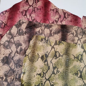 Puede incluir: Tres piezas de cuero de serpiente en diferentes colores y patrones. La pieza superior es de color rojo oscuro con un patrón sutil. La pieza del medio es de color marrón claro con un patrón marrón oscuro. La pieza inferior es de color verde claro con un patrón verde oscuro.