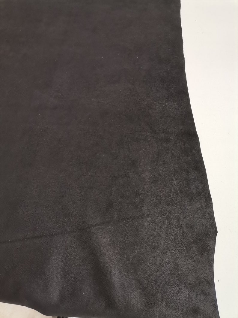 May include: A piece of black leather with a smooth, textured surface.