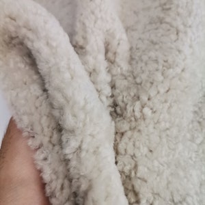 May include: Close-up of a soft, white, fluffy fabric with a textured surface. The fabric is folded in half, showing the texture of the material.