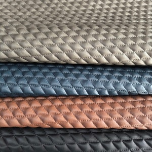 Peut inclure: Quatre morceaux de tissu matelassé de différentes couleurs : gris, bleu, marron et noir. Le tissu a un motif en losange.