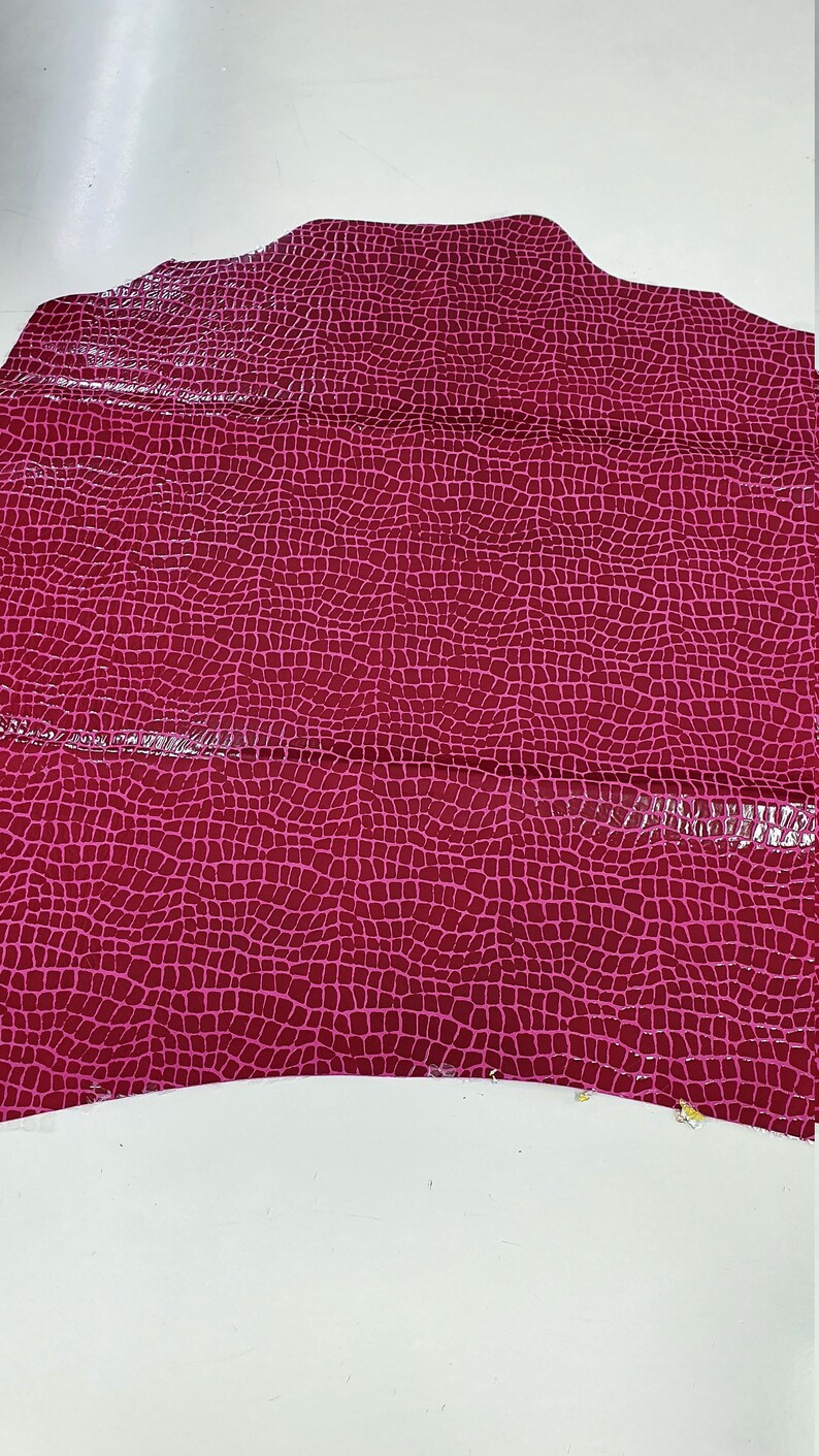May include: A piece of pink faux leather with a crocodile skin pattern.