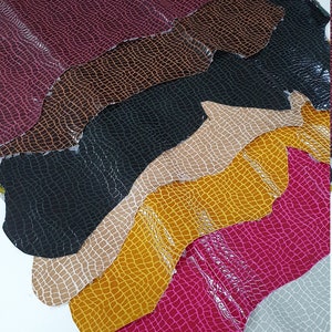 May include: A stack of eight different colored leather sheets with a crocodile skin pattern. The colors are burgundy, brown, black, beige, yellow, pink, gray, and brown.