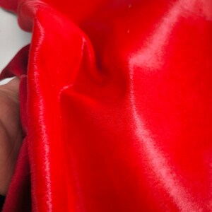 Pode incluir: Um close-up de uma pele de vaca vermelha brilhante com uma textura macia e felpuda.