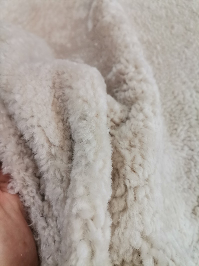 May include: Close-up of a soft, white faux fur fabric with a slightly textured surface.
