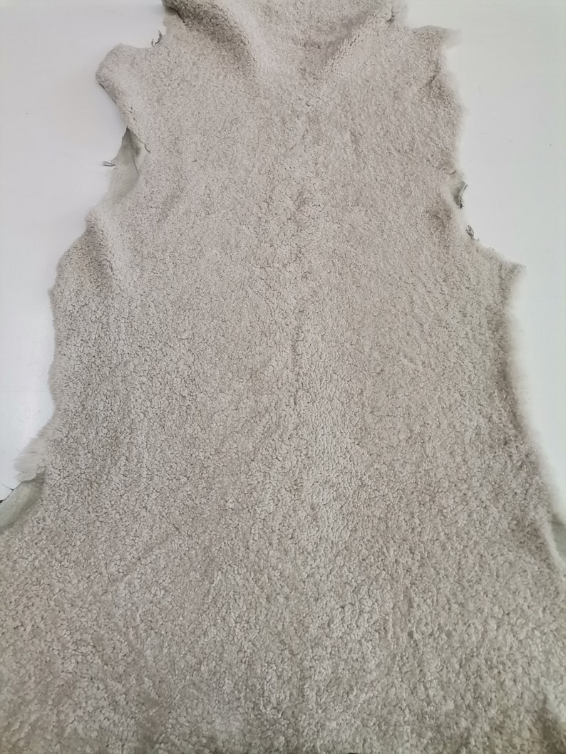 May include: A light gray sheepskin rug with a soft, fluffy texture.