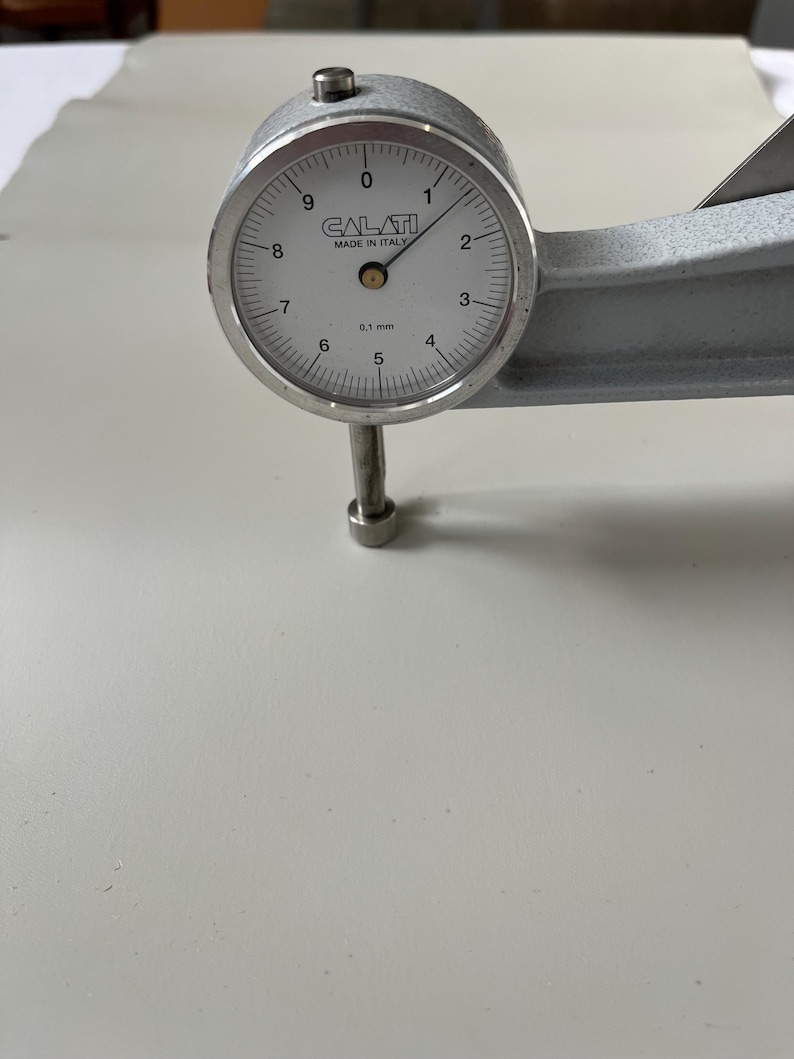 Puede incluir: Un medidor de dial plateado con una cara blanca y marcas negras. El medidor lee 0,1 mm y est&aacute; etiquetado como "CALATI MADE IN ITALY".
