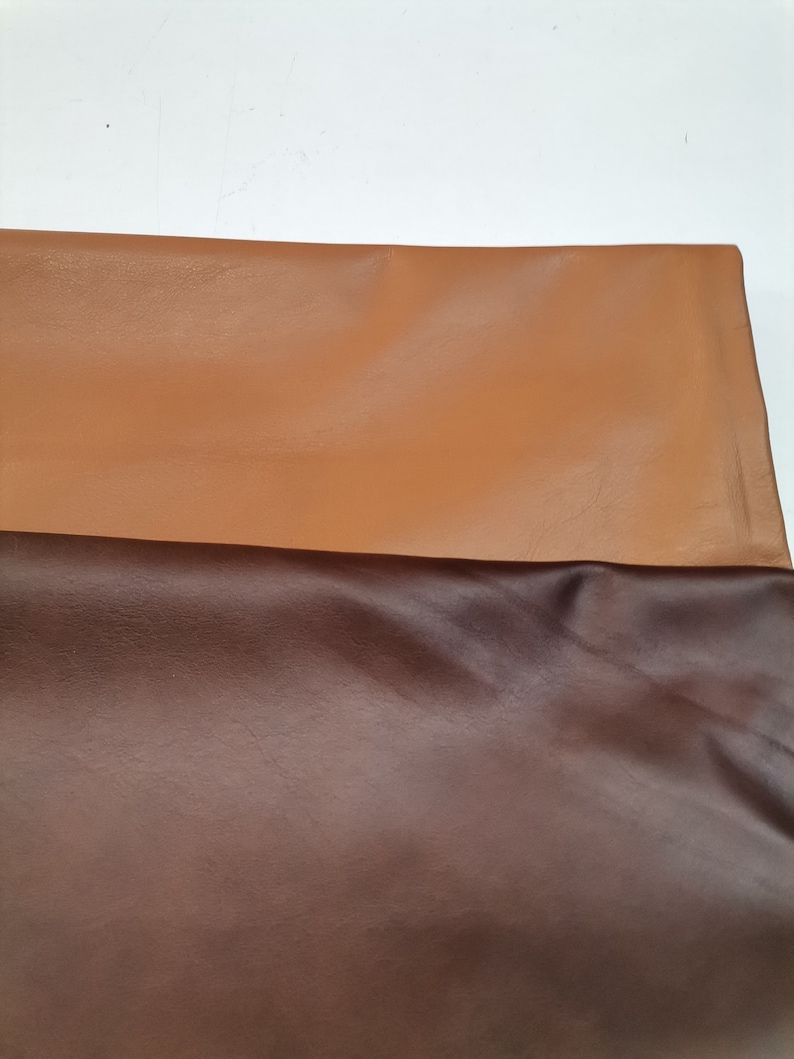Peut inclure: Deux morceaux de cuir, l'un brun et l'autre brun fonc&eacute;, sont dispos&eacute;s sur une surface blanche.