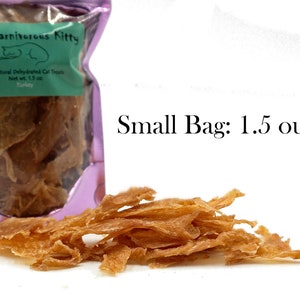 May include: A small purple bag with a label that reads "The Carnivorous Kitty" and "All Natural Dehydrated Cat Treats Turkey Net wt. 1.5 oz" with a pile of thin, light brown, dehydrated turkey cat treats in front of the bag. Small Bag: 1.5 ounces