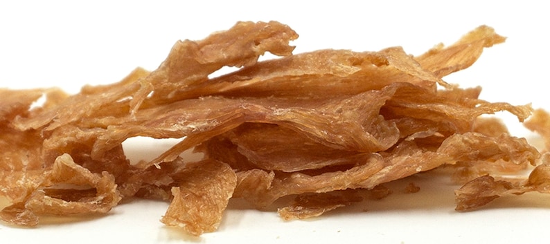 May include: A pile of thin, crispy, light brown chicken jerky strips.