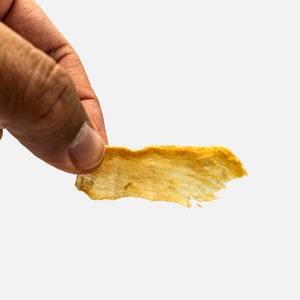 Puede incluir: Una sola viruta de fruta deshidratada, fina, crujiente, de color marr&oacute;n dorado, de forma irregular.