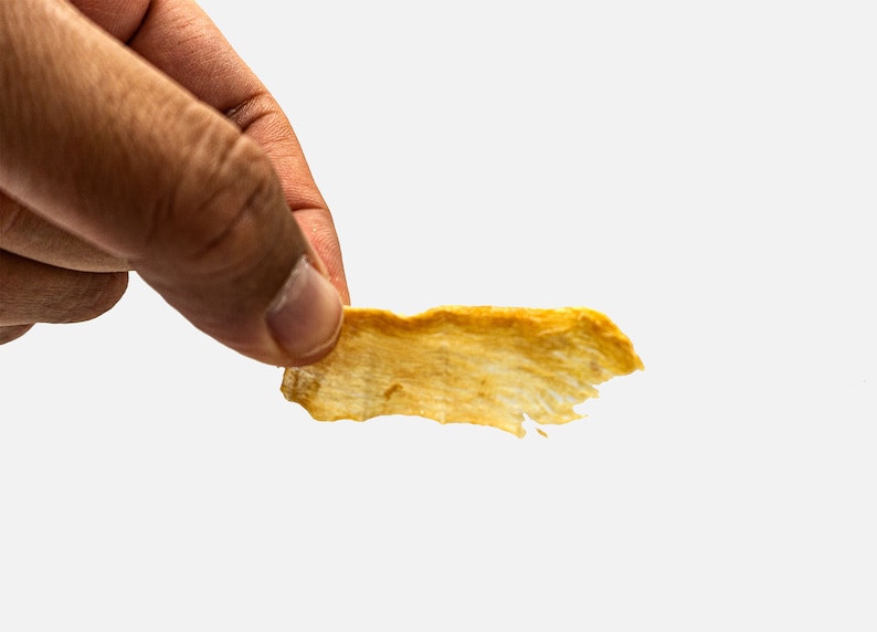 Puede incluir: Una sola viruta de fruta deshidratada, fina, crujiente, de color marr&oacute;n dorado, de forma irregular.