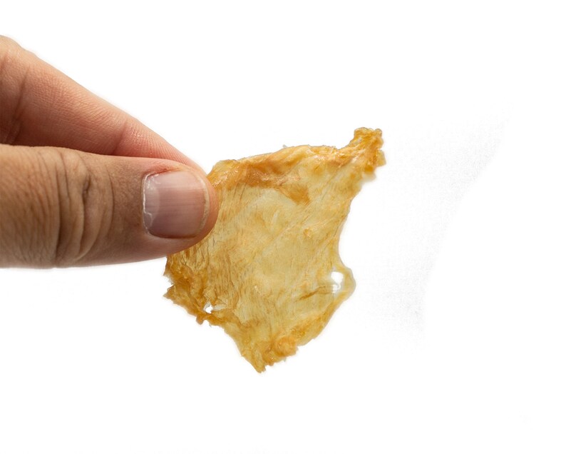 May include: A single, light brown, crispy, dried fish skin snack.