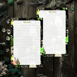 May include: Two rectangular stationery sheets featuring a black border with illustrations of white and black cats, green candles, mushrooms, and potion bottles. The top of each sheet displays the text My Notes in green, with one sheet lined.