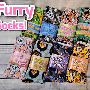 May include: A collection of eight colourful socks featuring various cartoon animal designs. The socks are all knee-high and have the text "Sock Your Paws!" printed on the packaging.