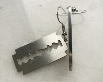 May include: A pair of silver earrings shaped like a razor blade.