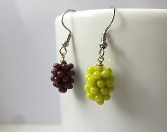 May include: A pair of dangle earrings featuring a cluster of purple and green beads, resembling grapes. The earrings have silver hooks.