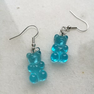 K&ouml;nnte beinhalten: Ein Paar silberne Ohrh&auml;nger mit blauen Gummib&auml;rchen-Anh&auml;ngern.