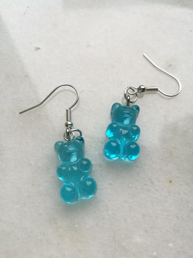 K&ouml;nnte beinhalten: Ein Paar silberne Ohrh&auml;nger mit blauen Gummib&auml;rchen-Anh&auml;ngern.