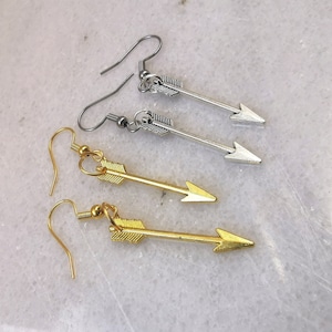 Puede incluir: Un par de pendientes de flecha plateados y un par de pendientes de flecha dorados. Los pendientes tienen todos la forma de una flecha con una punta puntiaguda.