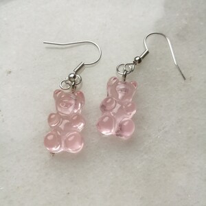 K&ouml;nnte beinhalten: Ein Paar silberne Ohrringe mit rosa Gummib&auml;rchen-Anh&auml;ngern.