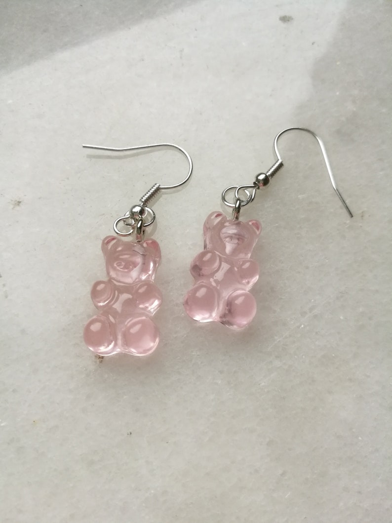 K&ouml;nnte beinhalten: Ein Paar silberne Ohrringe mit rosa Gummib&auml;rchen-Anh&auml;ngern.