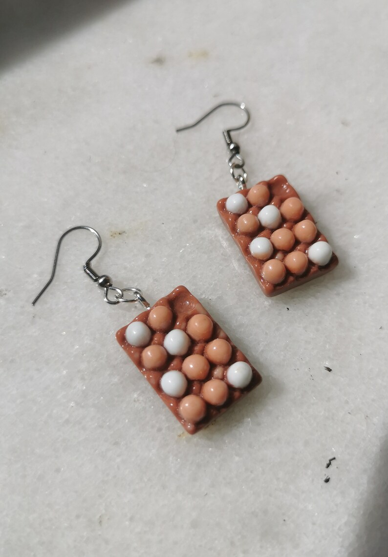 Peut inclure: Une paire de boucles d'oreilles en forme de bo&icirc;tes &agrave; &oelig;ufs avec des &oelig;ufs bruns et blancs. Les boucles d'oreilles sont en p&acirc;te polym&egrave;re et ont des crochets argent&eacute;s.
