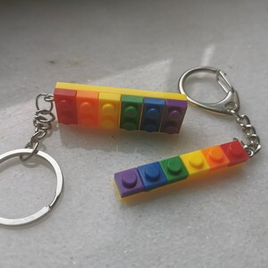 May include: A rainbow-colored keychain made of plastic LEGO bricks. The keychain has a silver ring and chain.