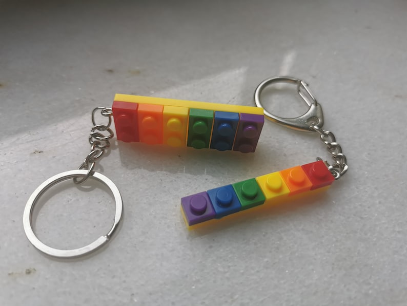 May include: A rainbow-colored keychain made of plastic LEGO bricks. The keychain has a silver ring and chain.