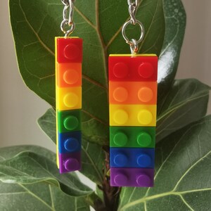 May include: Two rainbow-colored Lego brick keychains with silver chains. The bricks are stacked in the order of the rainbow, red, orange, yellow, green, blue, and purple.