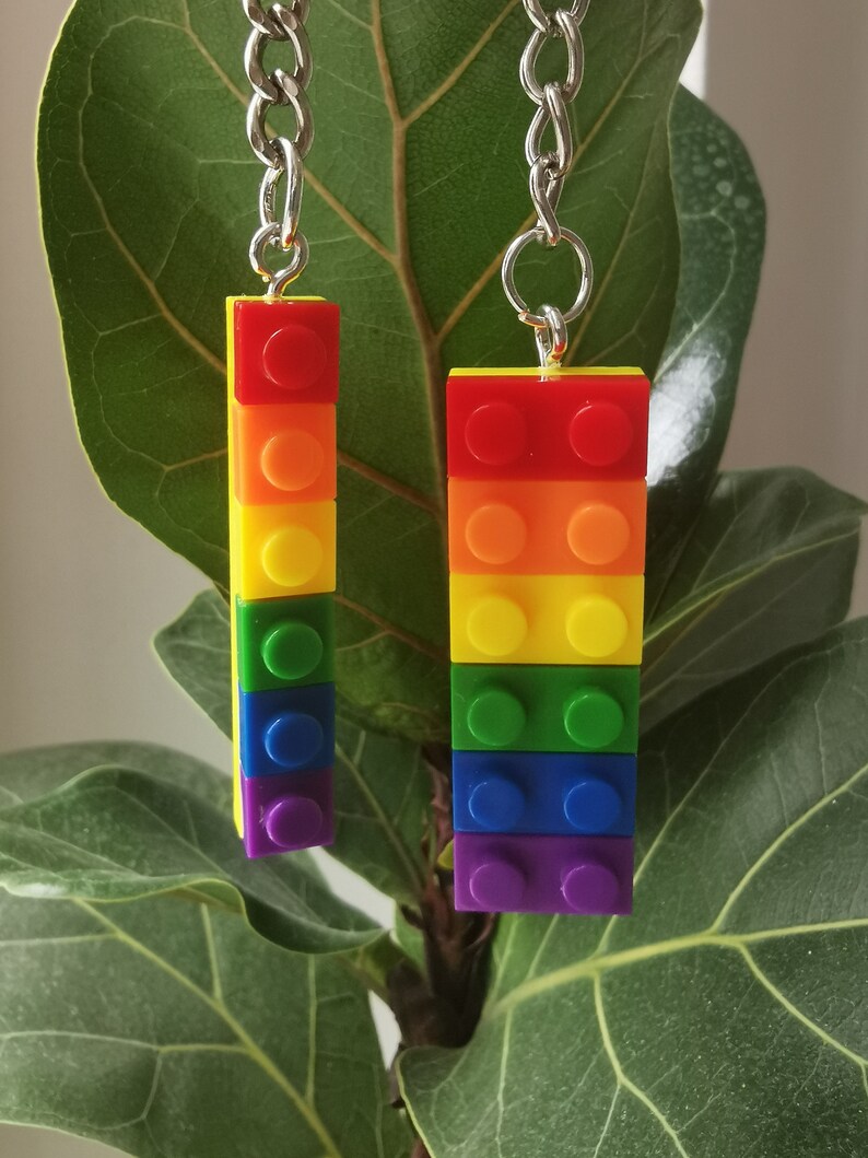 May include: Two rainbow-colored Lego brick keychains with silver chains. The bricks are stacked in the order of the rainbow, red, orange, yellow, green, blue, and purple.