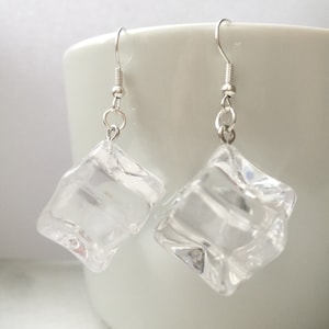 May include: A pair of silver dangle earrings with clear, cube-shaped charms that resemble ice cubes.