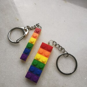May include: Two rainbow-colored keychain charms made of plastic building blocks. Each charm is attached to a silver key ring.
