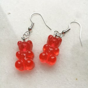 K&ouml;nnte beinhalten: Ein Paar rote Gummib&auml;rchen-Ohrringe mit silbernen Haken.