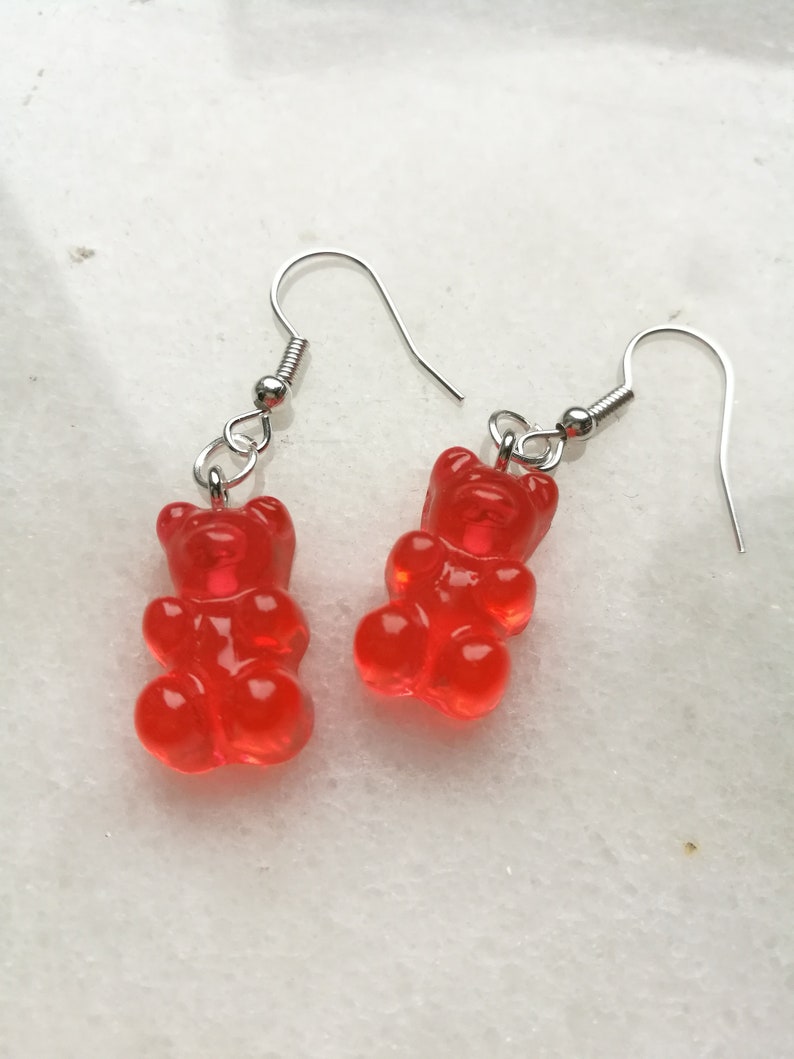K&ouml;nnte beinhalten: Ein Paar rote Gummib&auml;rchen-Ohrringe mit silbernen Haken.