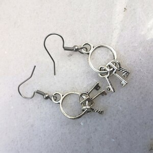 May include: Silver key earrings with a circle design and multiple keys dangling from the bottom.