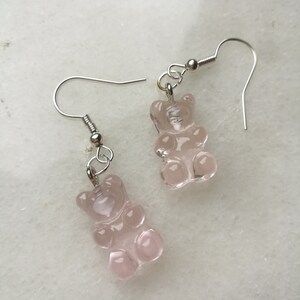 K&ouml;nnte beinhalten: Ein Paar silberne Ohrringe mit rosa Gummib&auml;rchen-Anh&auml;ngern.