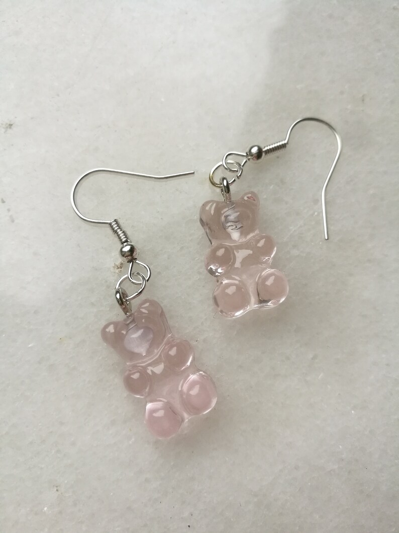 K&ouml;nnte beinhalten: Ein Paar silberne Ohrringe mit rosa Gummib&auml;rchen-Anh&auml;ngern.