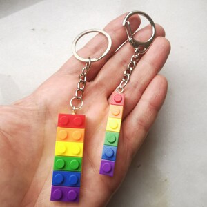 May include: Two rainbow-colored keychain charms made of stacked Lego bricks. The charms are attached to silver key rings.