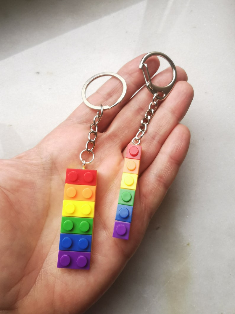 May include: Two rainbow-colored keychain charms made of stacked Lego bricks. The charms are attached to silver key rings.
