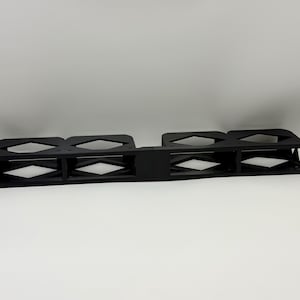 May include: A black rack mount shelf with diamond-shaped cutouts. The shelf has a rectangular shape with mounting holes on each end. The design is symmetrical, with four sections separated by vertical supports.