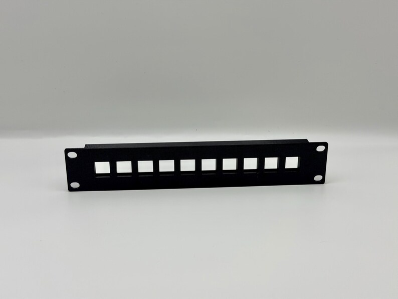 May include: A black, rectangular patch panel with ten square openings. The panel has two holes on each end for mounting. The item is designed for network or data cable management.