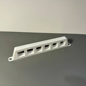 Peut inclure: Support mural en plastique blanc avec six ouvertures rectangulaires.